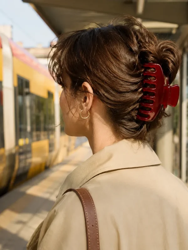 Woman on a tram platform with her hair up in a cherry claw clip